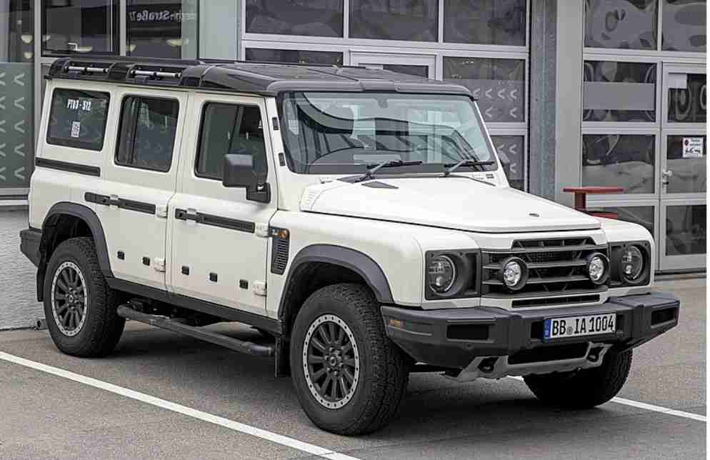 A silver Mercedes-Benz G-Class SUV parked on a cobblestone street near historical buildings.